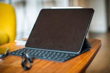 Tablette avec un clavier et un stylet sur une table en bois, photo d’illustration