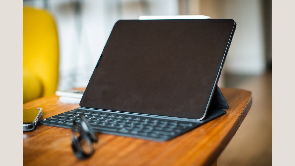 Tablette avec un clavier et un stylet sur une table en bois, photo d’illustration