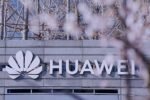 Enseigne Huawei sur la façade d’un bâtiment, devant des arbres en fleurs