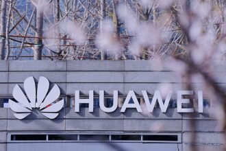 Enseigne Huawei sur la façade d’un bâtiment, devant des arbres en fleurs