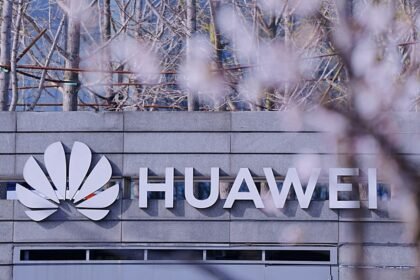 Enseigne Huawei sur la façade d’un bâtiment, devant des arbres en fleurs