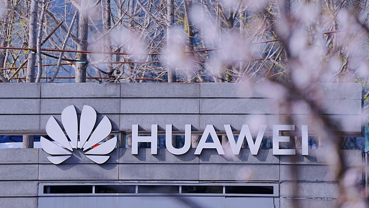 Enseigne Huawei sur la façade d’un bâtiment, devant des arbres en fleurs