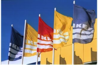 Drapeaux IKEA bleus, jaunes et rouge devant une façade jaune
