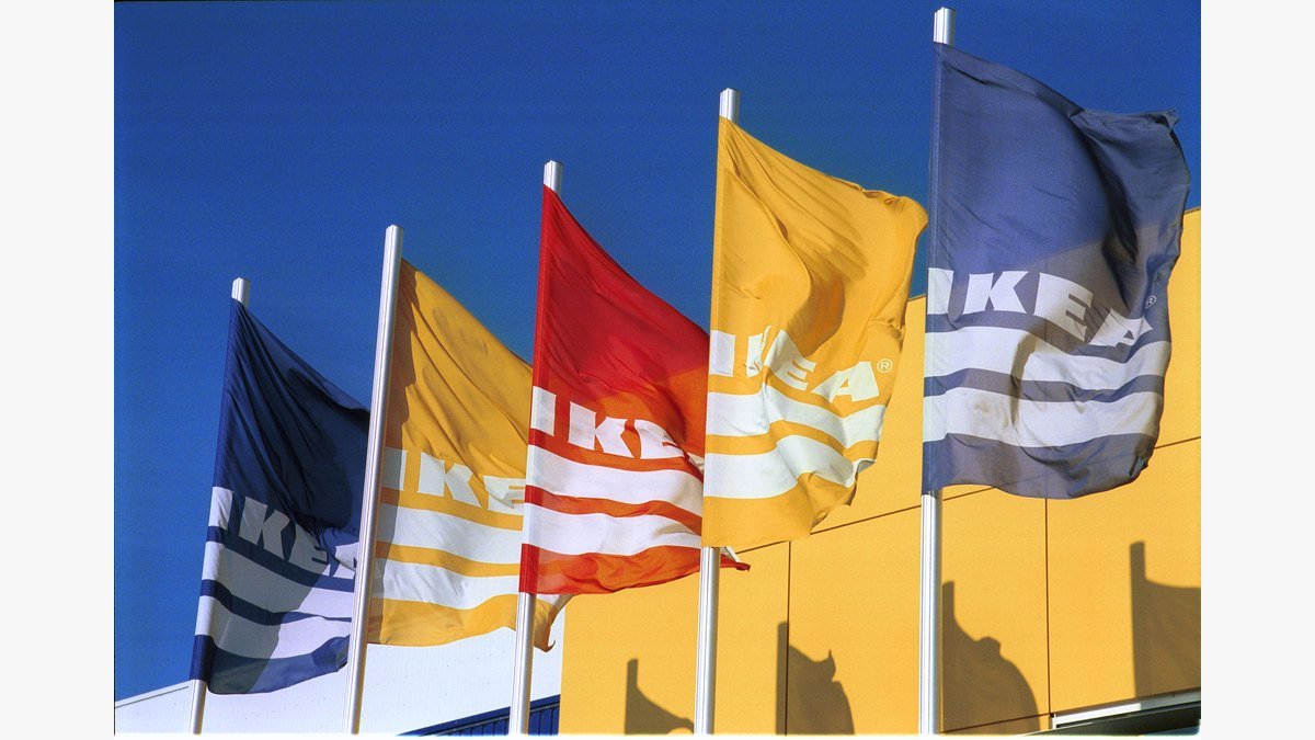 Drapeaux IKEA bleus, jaunes et rouge devant une façade jaune