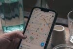 Téléphone affichant Google Maps, tenu au-dessus d’une table de café