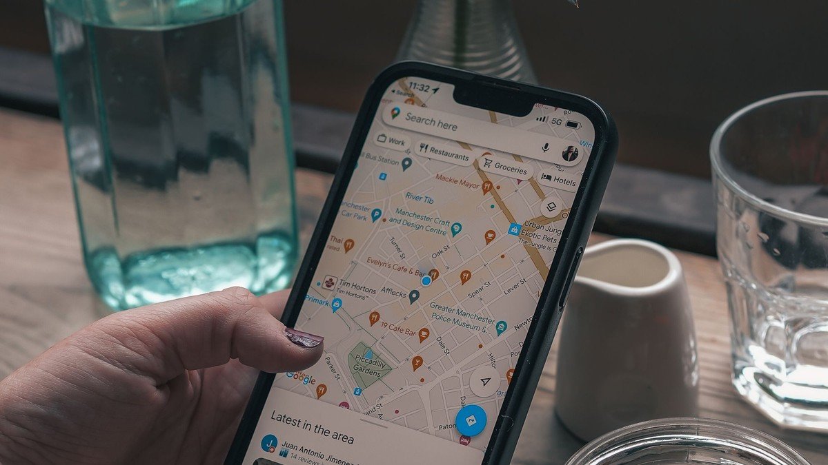 Téléphone affichant Google Maps, tenu au-dessus d’une table de café