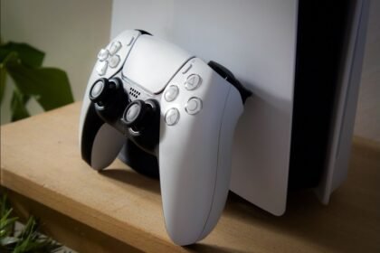 Une manette DualSense blanche posée devant une console PlayStation 5