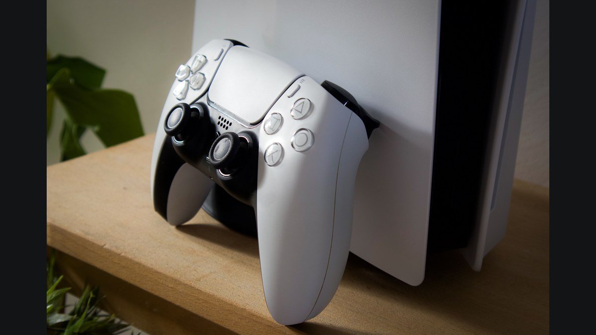 Une manette DualSense blanche posée devant une console PlayStation 5