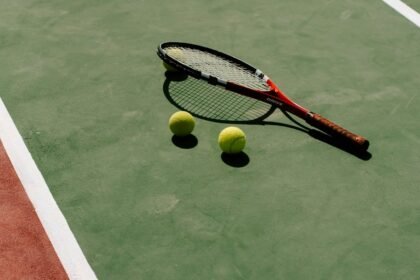 Une raquette et des balles de tennis posées sur un court vert