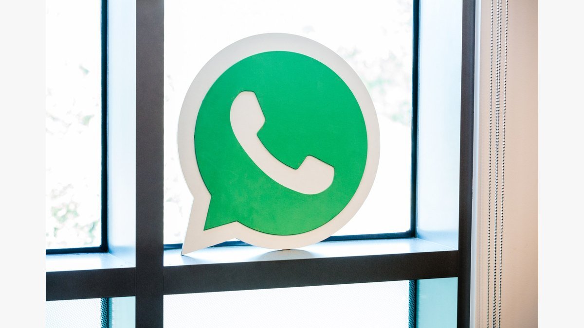 Enseigne verte WhatsApp posée devant une fenêtre dans les locaux de Facebook