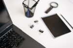 Ordinateur portable noir posé sur un bureau avec un carnet