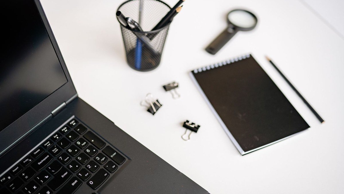 Ordinateur portable noir posé sur un bureau avec un carnet