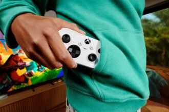 Manette Xbox Nano blanche glissée dans la poche d’un sweat vert