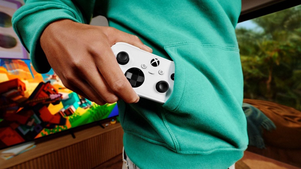 Manette Xbox Nano blanche glissée dans la poche d’un sweat vert